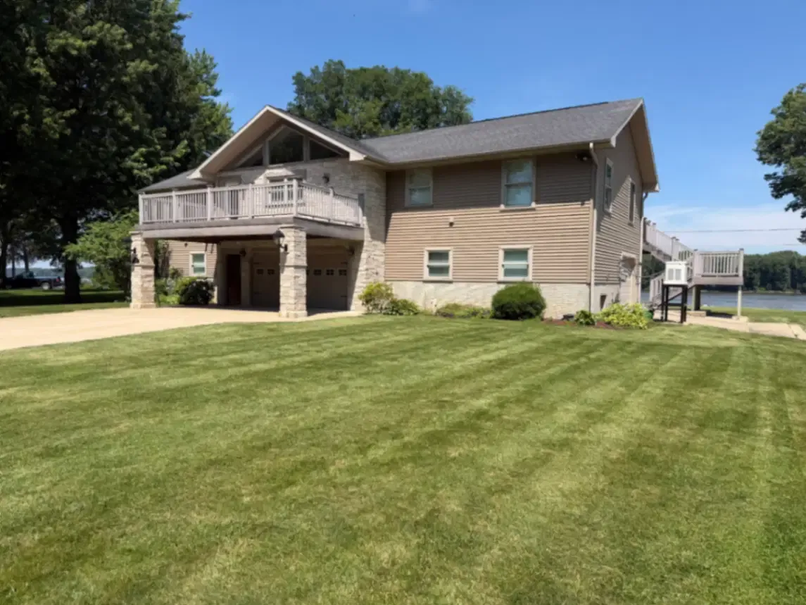 Residential lawn service with crisp mowing stripes at a riverside home in Clinton, Iowa